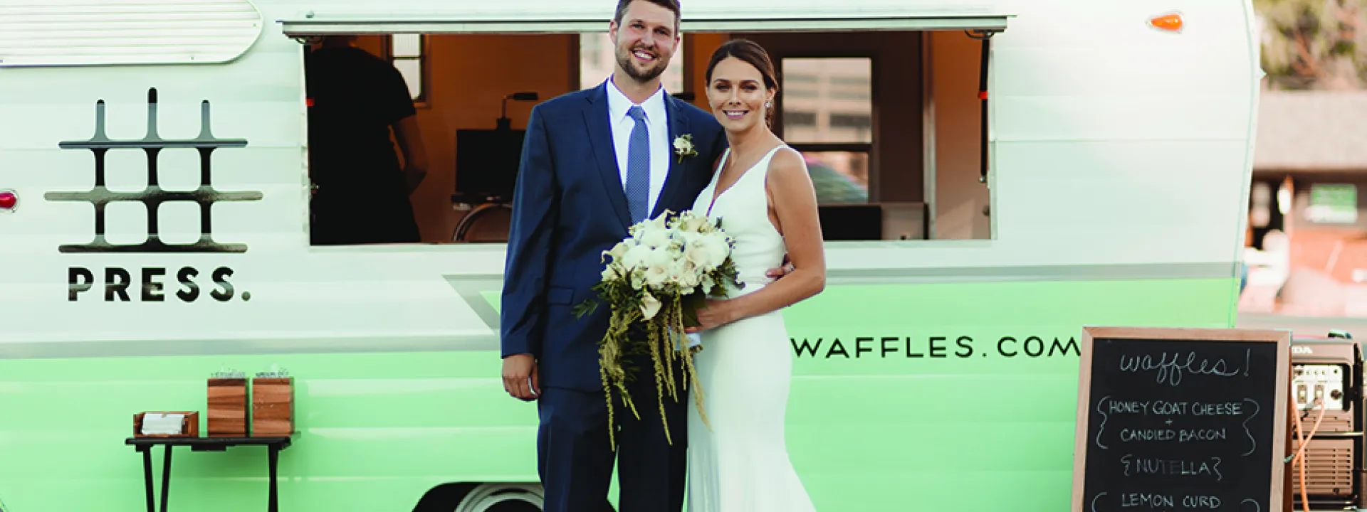 A couple stands in front of Belgian Liege Waffles, part of a new wedding trend: food stations.
