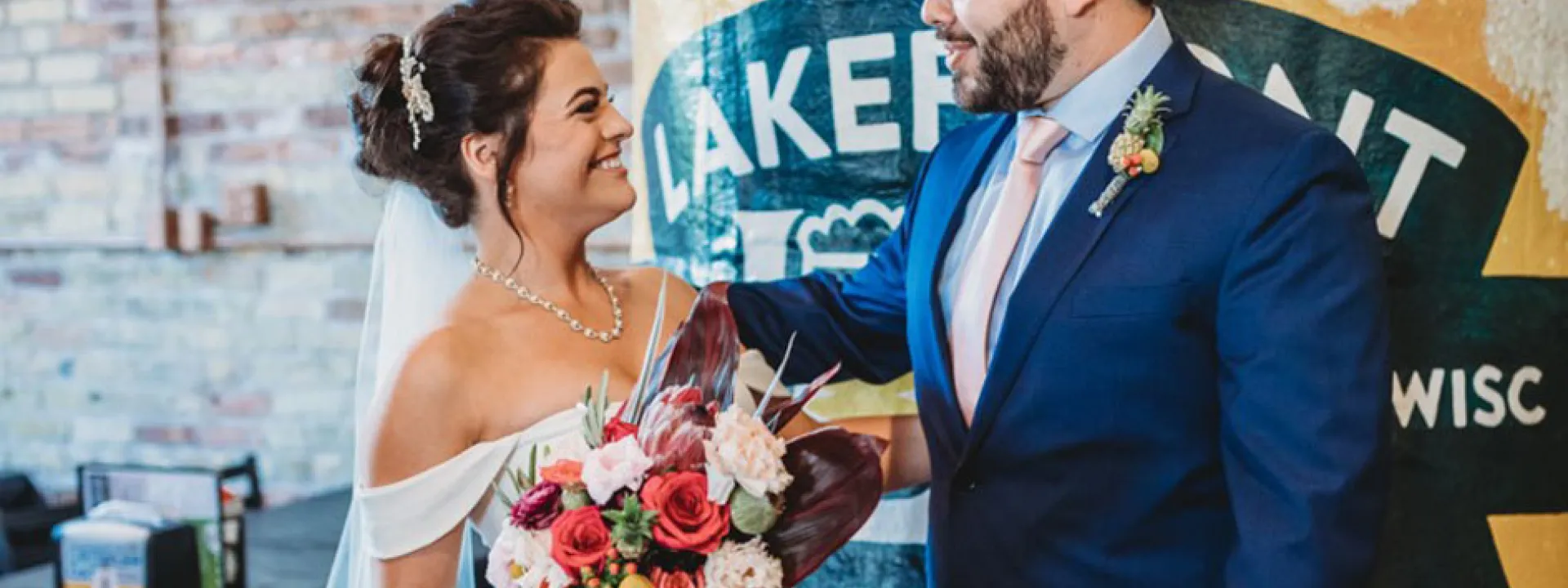 The bride, holding her homemade bouquet, with the groom at Lakefront Brewing in Milwaukee