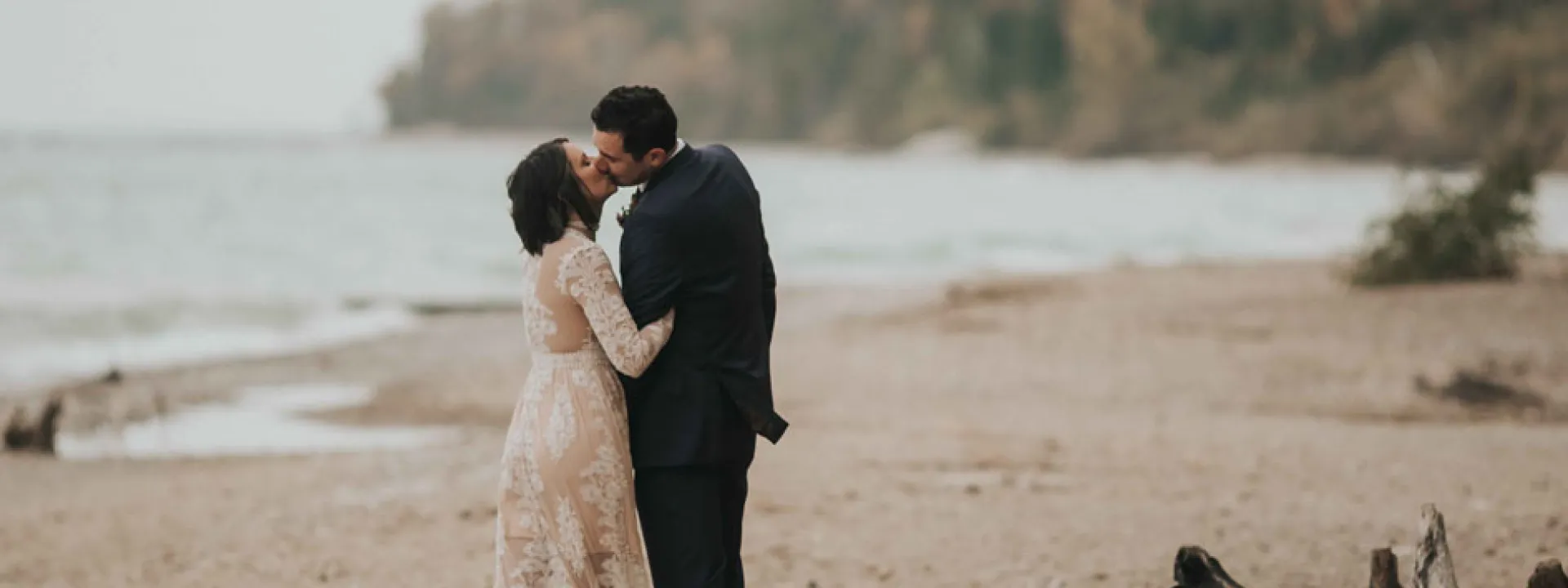 The bride, wearing Free People, kisses her groom on the beach at Grant Park