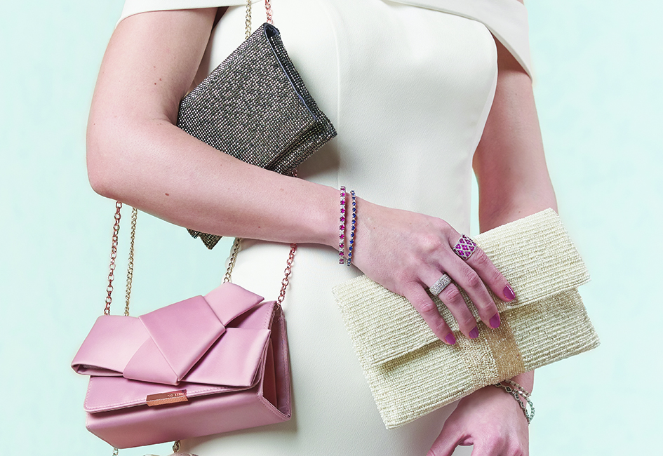 A bride holds three different bridal clutches: pewter, pink and ivory.
