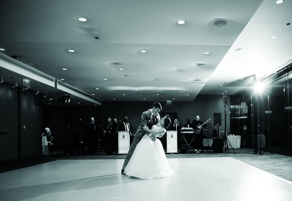 A couple performs their first dance at their wedding while a band plays in the background.