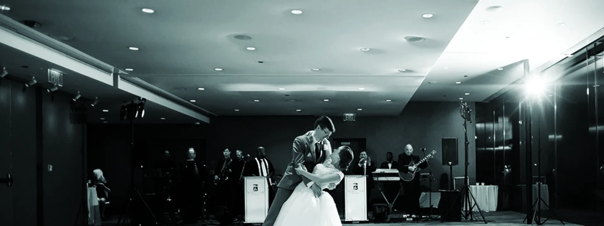 A couple performs their first dance at their wedding while a band plays in the background.